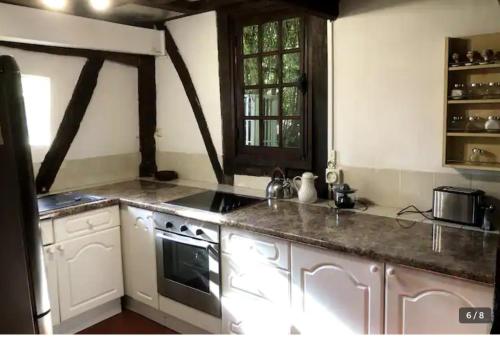 une cuisine avec des armoires blanches et un four à plaques de cuisson dans l'établissement Le gîte du Manoir Normand, à Saint-Philbert-des-Champs