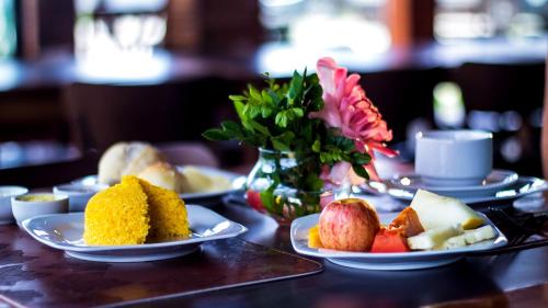 een tafel met borden en een vaas met bloemen bij Refúgio do Rio Bonito in Bonito