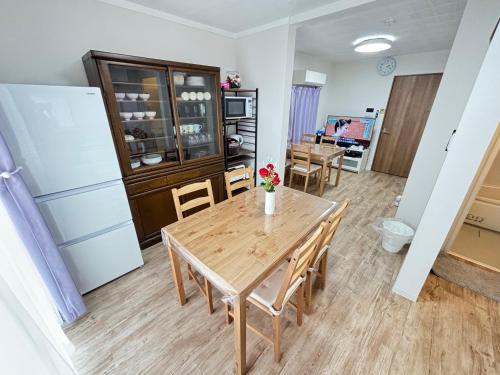 a kitchen with a wooden table and a refrigerator at NEYAGAWA HOUSE!, It is red cute house at 3 min walk from Keihan Kayashima Station, 京阪電車 萱島駅から徒歩3分の所にある赤いかわいい一棟貸しの家です, 家の前の駐車場はサイズ制限あり, サイズ超過は徒歩1分のコインパーキングをご利用下さい, in Neyagawa