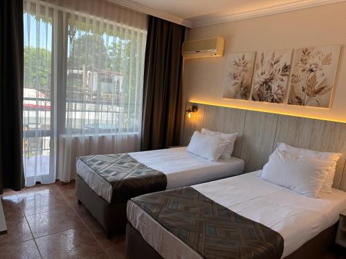 a hotel room with two beds and a window at Oleander House and Tennis Club in Sunny Beach