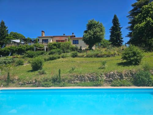 une maison sur une colline avec une piscine bleue dans l'établissement Maison Les Fraysses, à Bellefont-La Rauze