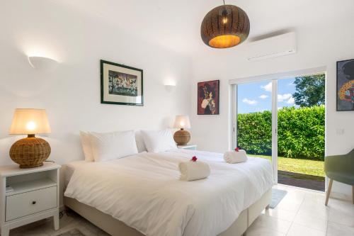a bedroom with a bed with white sheets and a window at Casa Rosella in Carvoeiro