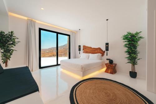 a bedroom with a bed and a large window at Mega Mansions Mykonos in Elia
