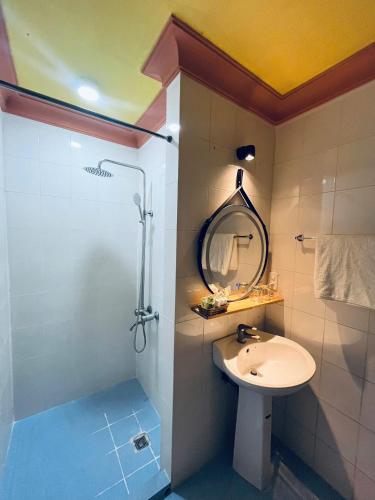 a bathroom with a sink and a shower with a mirror at Na Nue Hotel in Ho Chi Minh City
