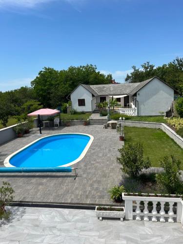 a backyard with a swimming pool and a house at Főnix Apartmanház in Vonyarcvashegy