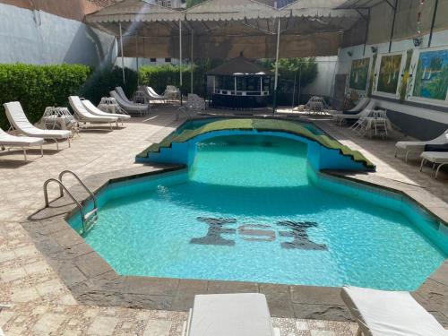 a large swimming pool with chairs and an umbrella at Shady Hotel Luxor in Luxor