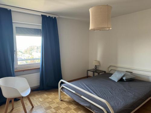a bedroom with a bed and a chair and a window at Best view in Town in Köniz