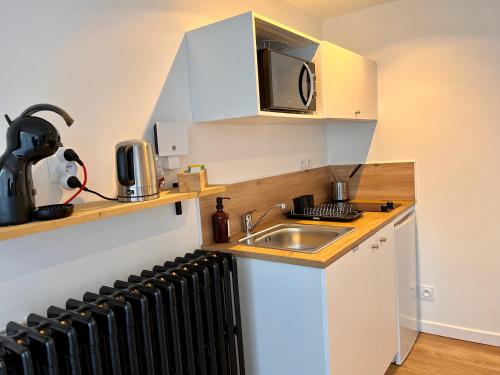 a small kitchen with a sink and a microwave at Le Quarante cinq -5 in Laval