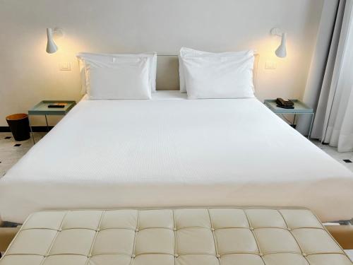 a large white bed in a room with two tables at Hotel Le Nuvole Residenza d'Epoca in Genoa