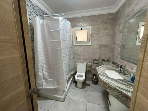 a bathroom with a shower and a toilet and a sink at شقه فندقيه الداون تاون العلمين الجديده بجوار بالم هيلز والابراج in El Alamein