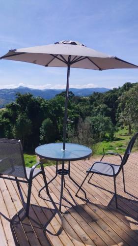 a table and two chairs with an umbrella on a deck at Montanha Home in Monte Verde