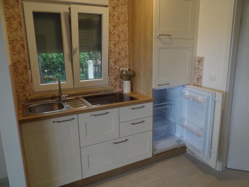 eine Küche mit weißen Schränken, einer Spüle und einem Kühlschrank in der Unterkunft Adriatic Houses Borse in Bašanija