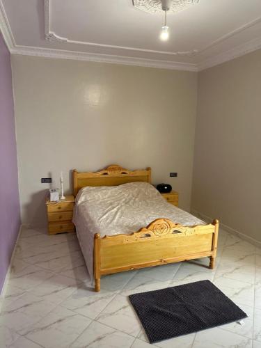 a bedroom with a wooden bed and two night stands at Spacieux Appartement Selouane Nador in Selouane