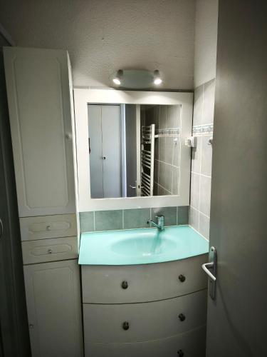 une salle de bain avec un lavabo et un miroir dans l'établissement Appartement 50 m2 climatisé en front de mer, plage à 10m, à Saint Cyprien Plage