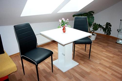 a white table with three chairs and a vase with flowers at Ubytování Sušice in Sušice