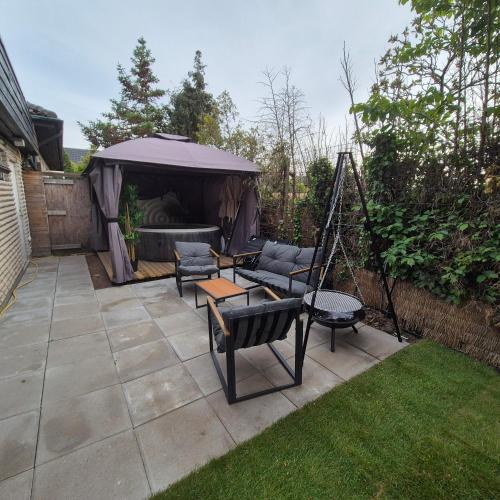 a garden with a gazebo with a couch and chairs at SO Easy Stay, Malmö in Malmö