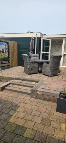 a patio with chairs and a table with an umbrella at Huis bij het water in uitstekend fiets-, vis- en vaargebied in Jutrijp