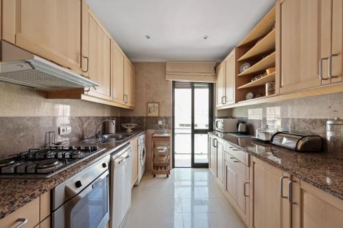a large kitchen with wooden cabinets and stainless steel appliances at BmyGuest - Sesimbra Palames Beach & Pool Apartment in Sesimbra