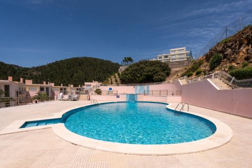 a swimming pool in the middle of a resort at BmyGuest - Sesimbra Palames Beach & Pool Apartment in Sesimbra
