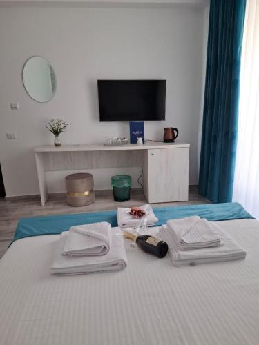 a bedroom with a bed with towels and a tv at RUXO Hotel in Mamaia Nord