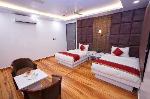ein Hotelzimmer mit zwei Betten und einem Tisch in der Unterkunft Sara Fortune International in Noida