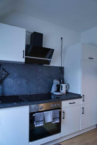 a kitchen with white cabinets and a stove top oven at Heide Ferienwohnung West Nr-4 in Schneverdingen