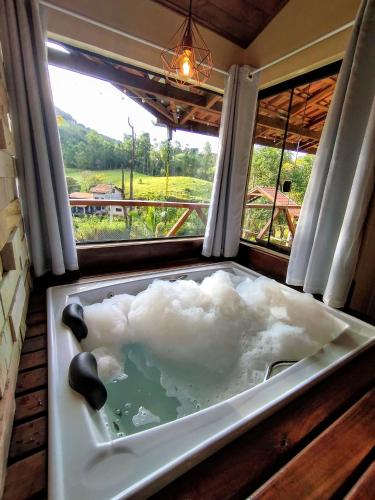 a bath tub with a cloud in it with a window at Estação 160 chalé Pico Agudo in Santo Antônio do Pinhal