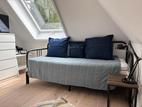 a bedroom with a bed with blue pillows and a window at Zum Schwedenblick in Zingst