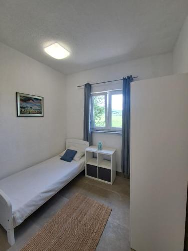 a small bedroom with a bed and a window at Apartman Mia in Perušić