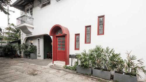 a red door on a white building with plants at MiraNamin Nest ROSAL Suite in Unique Historic Home - Garden View, Shared Kitchen in Manila