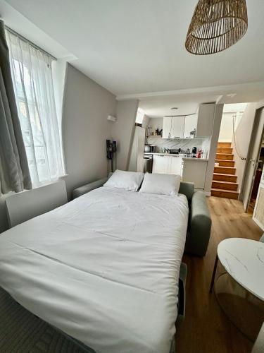 une chambre avec un grand lit blanc et une cuisine dans l'établissement La belle Deauvillaise, à Deauville