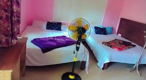 a room with two beds with a fan on a floor at Green porticos villa munnar #MUNNAR in Anachal