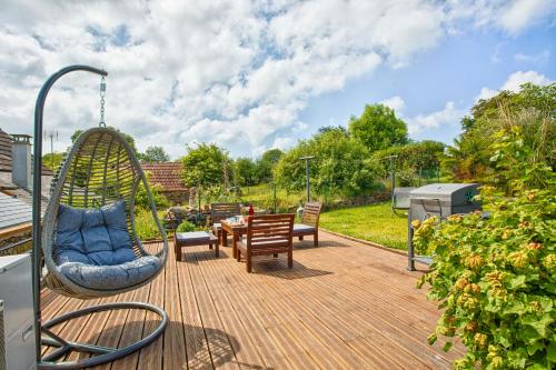 une terrasse avec une balançoire, une table et des chaises dans l'établissement Gîte 