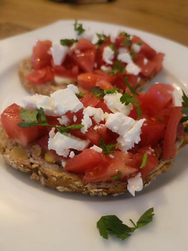 a sandwich with tomatoes and feta cheese on a plate at Pokoje u Daniela in Miedzygorze