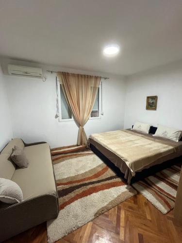 a bedroom with two beds and a couch at R&S two bedroom apartment in Podgorica