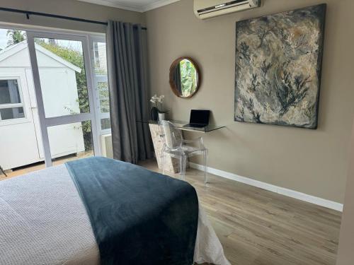 ein Schlafzimmer mit einem Bett und einem Schreibtisch mit einem Laptop in der Unterkunft The Cottage on Alphen in Heathfield