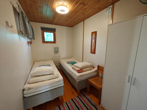 two beds in a small room with a wooden ceiling at Pyhtään Vuokramökit in Tuuski