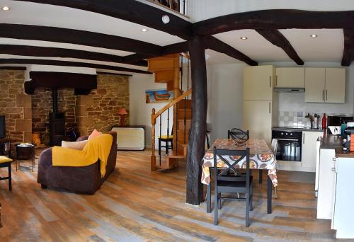un salon avec un canapé et une table et une cuisine dans l'établissement Charmante maison bretonne, à Séglien