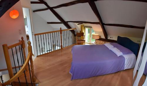 - une chambre mansardée avec un lit et des draps violets dans l'établissement Charmante maison bretonne, à Séglien