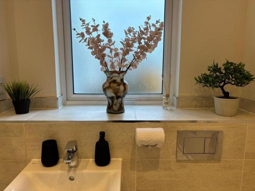 a vase of flowers sitting on a window sill next to a sink at Modern spacious apartment in Addlestone in Addlestone