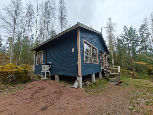 a blue house in the middle of a forest at Pyhtään Vuokramökit in Tuuski