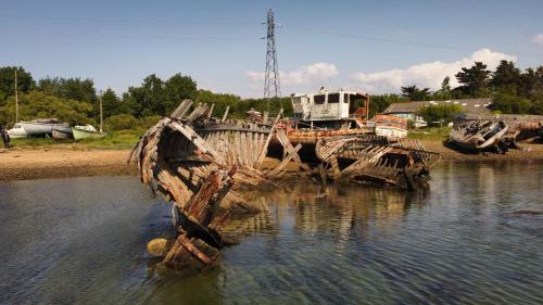 un vieux bateau est assis dans l'eau dans l'établissement Maison artistes bord de mer Rostellec, à Crozon