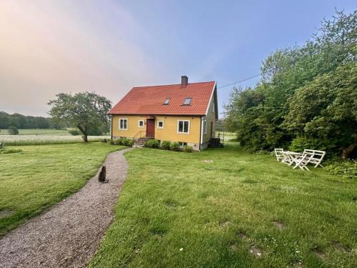 a yellow house with a red roof in a field at Yxnaholma Rum in Höör