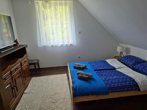 a bedroom with a blue bed with two brown shoes on it at Domek na Mazurach-Piasutno in Piasutno