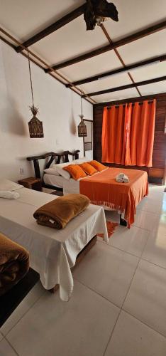 a room with three beds and orange curtains at Pousada Cabanas Paraiso in Ilha Grande