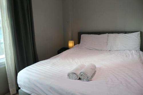 a white bed with towels on it with a window at Nato House Ekkamai -BTS Ekkamai with balcony in Bangkok
