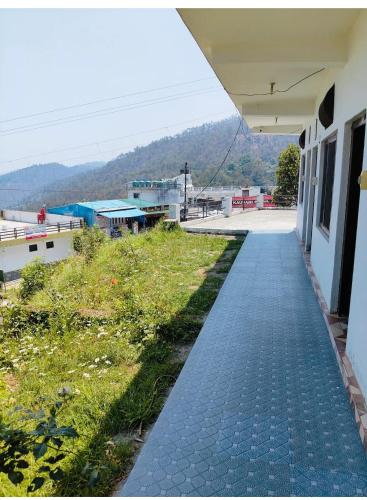 a brick walkway next to a building with a field at Shubham Home Stay in Kausani