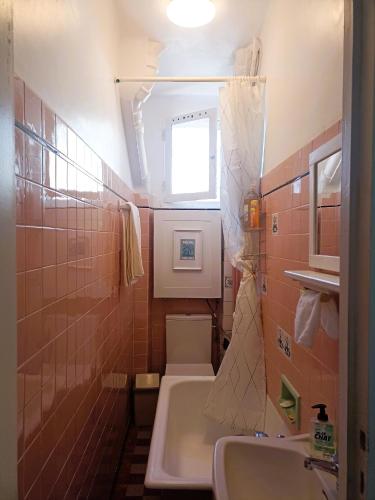une salle de bain avec un lavabo et des toilettes et une fenêtre dans l'établissement Votre pied-à-terre parisien bien connecté, à Paris