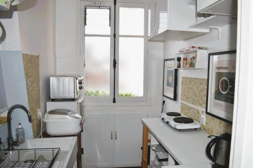 une petite cuisine avec un évier et une fenêtre dans l'établissement Votre pied-à-terre parisien bien connecté, à Paris