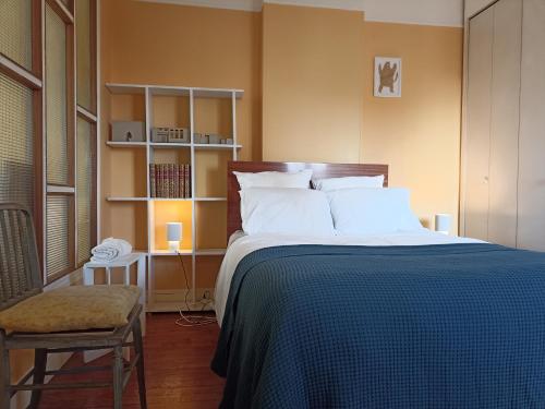 - une chambre avec un lit doté d'une couverture bleue et d'une chaise dans l'établissement Votre pied-à-terre parisien bien connecté, à Paris